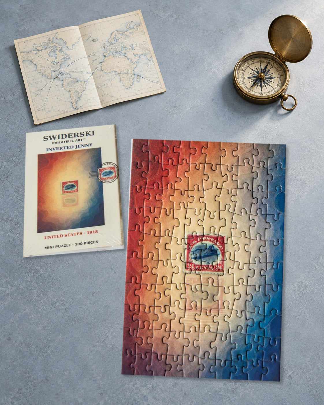 Inverted Jenny mini puzzle and packaging on a blue-grey archive table with a vintage route map and brass compass. Lifestyle montage using the original product photograph.