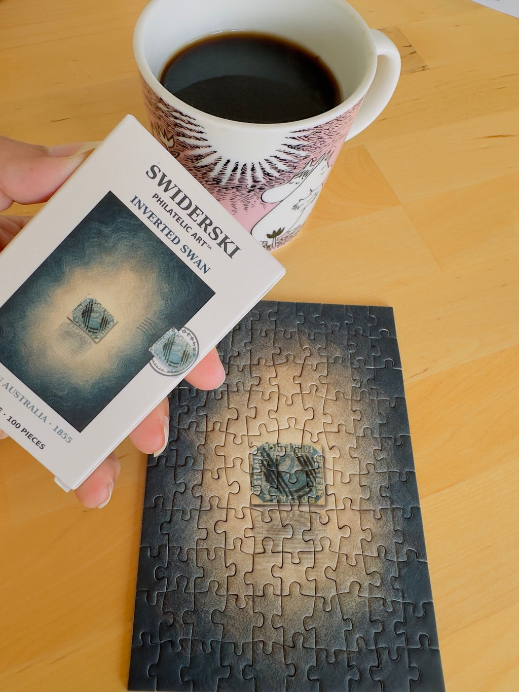 Inverted Swan mini puzzle and its box during a coffee break. Cup used as a photographic prop.