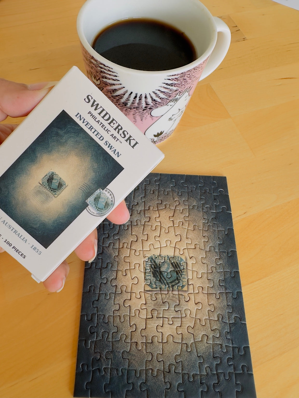 Inverted Swan mini puzzle and its box during a coffee break. Cup used as a photographic prop.