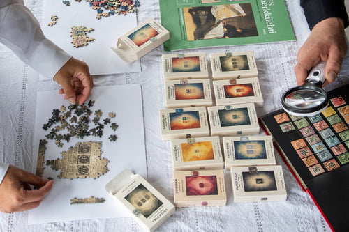 The Swiderski mini puzzle collection beside a stamp album, with puzzles being assembled. Collection photograph; each mini puzzle is sold individually.